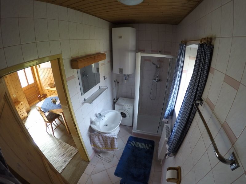 Badezimmer mit Dusche, Waschbecken, Waschmaschine und blauen Vorhängen.