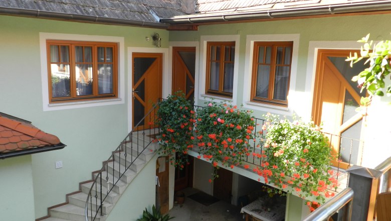 Innenhof mit Treppe, Blumen und Tisch.