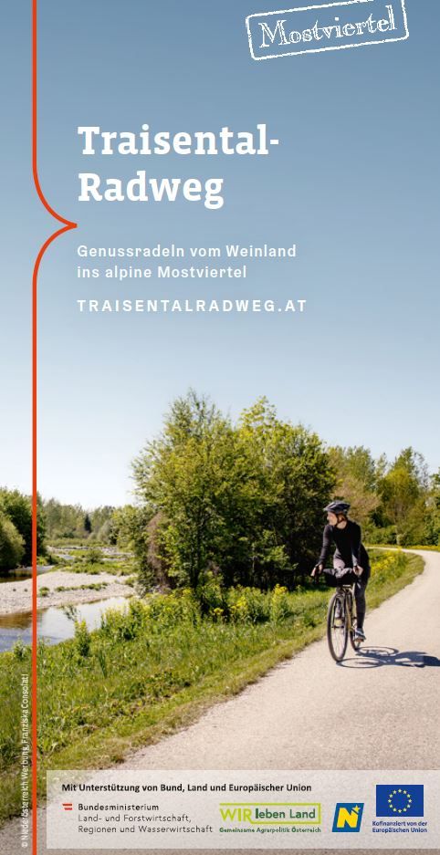 Coverbild: Eine Person fährt auf dem Rad neben dem Flussufer entlang des Traisental-Radwegs und blickt auf die Traisen. 