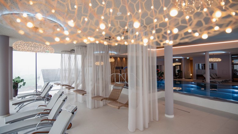 Moderner Spa-Ruhebereich mit Liegest&uuml;hlen, H&auml;ngesesseln und Pool.