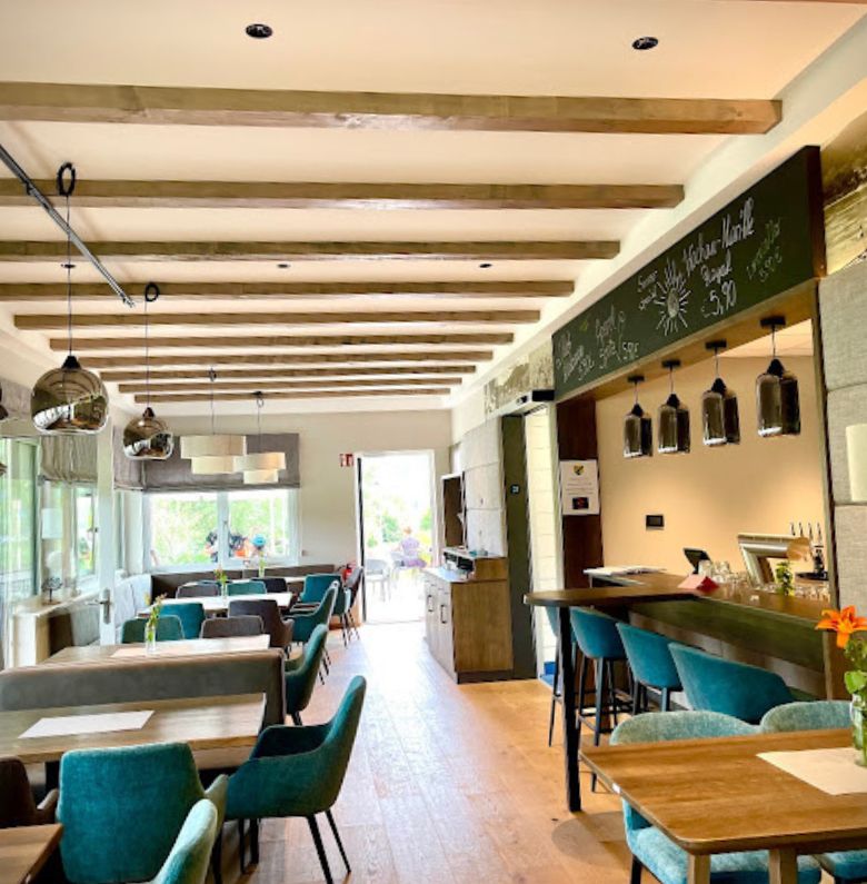 Restaurantbereich innen mit Tischen und grünen Sesseln