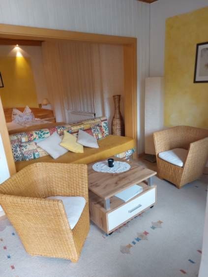 Gemütliches Gästezimmer mit Rattanmöbeln und buntem Sofa.