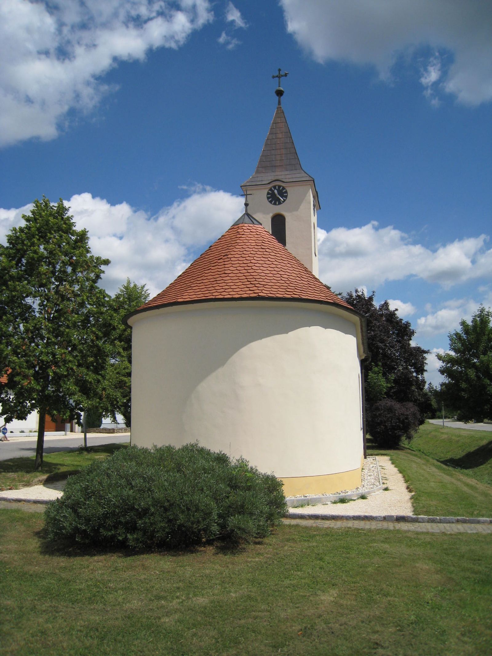 Ortskapelle Hl. Barbara mit rundem Dach und Turm vor blauem Himmel.