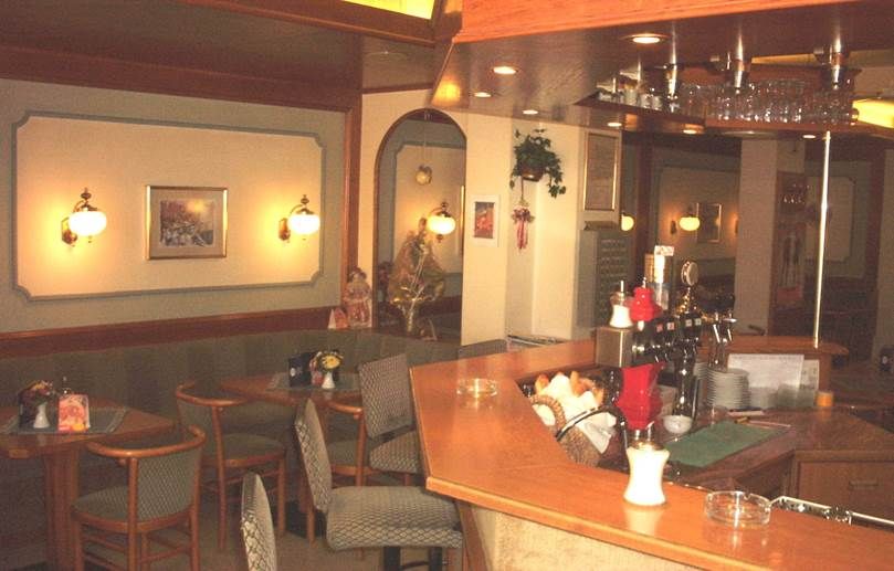 Innenansicht eines gemütlichen Cafés mit Holztresen und Sitzbereichen.