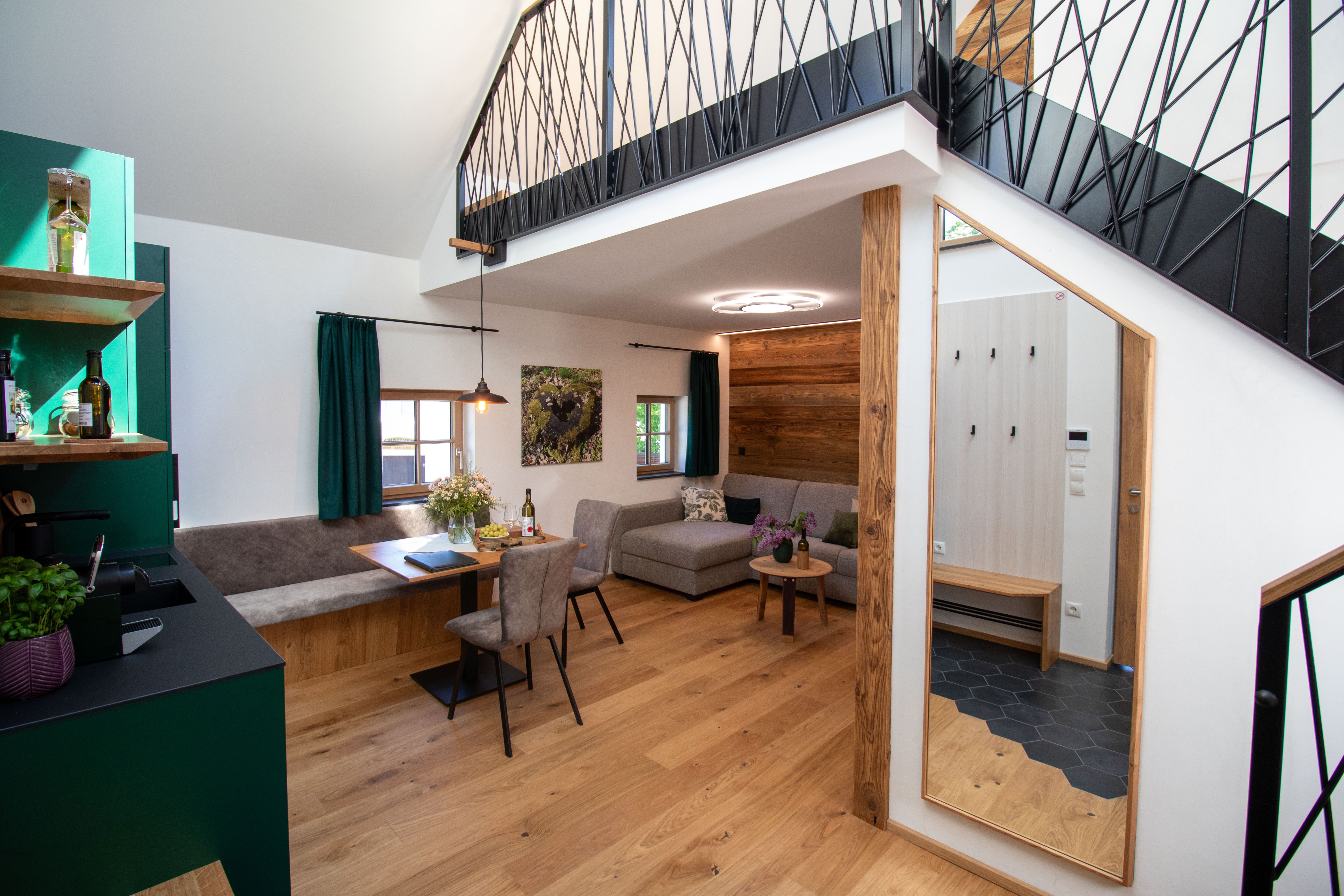 Modernes Apartment mit Holzboden, grauem Sofa, Esstisch und offener Galerie.