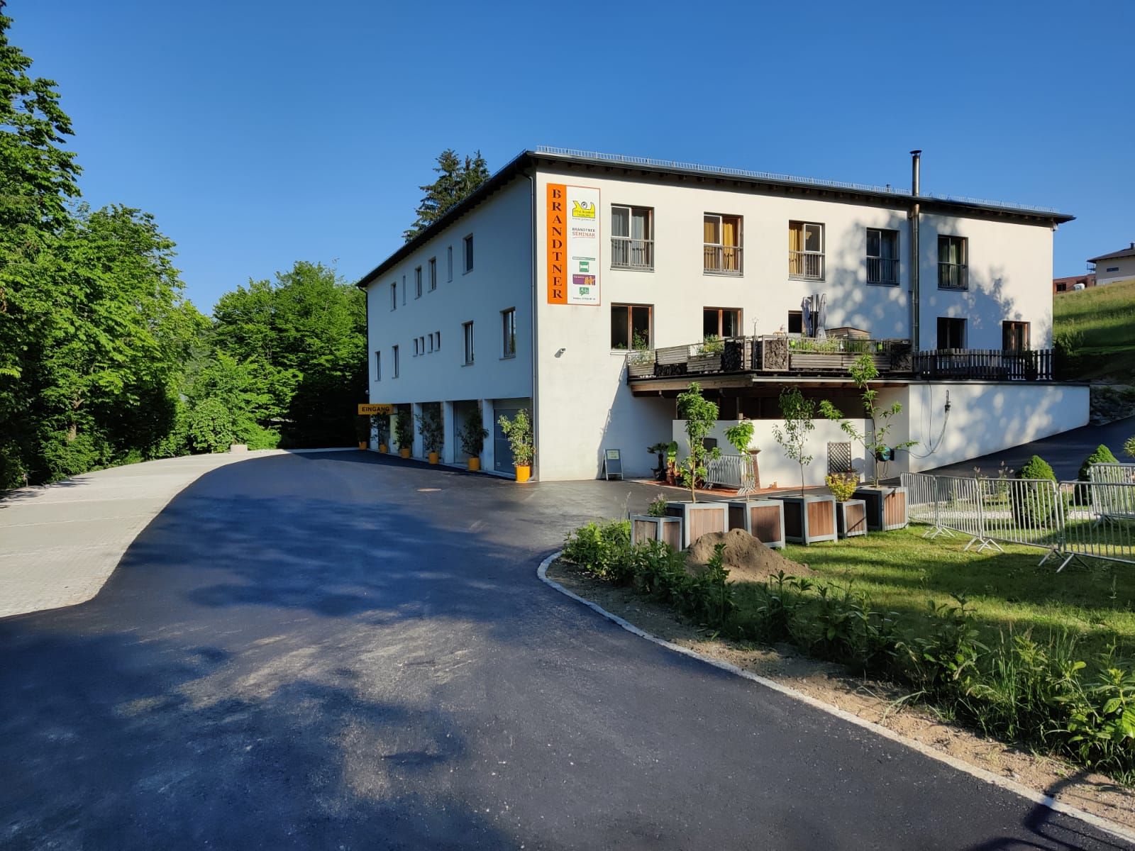 Gebäude mit der Aufschrift 'Brandtner', umgeben von Bäumen und einem Parkplatz.