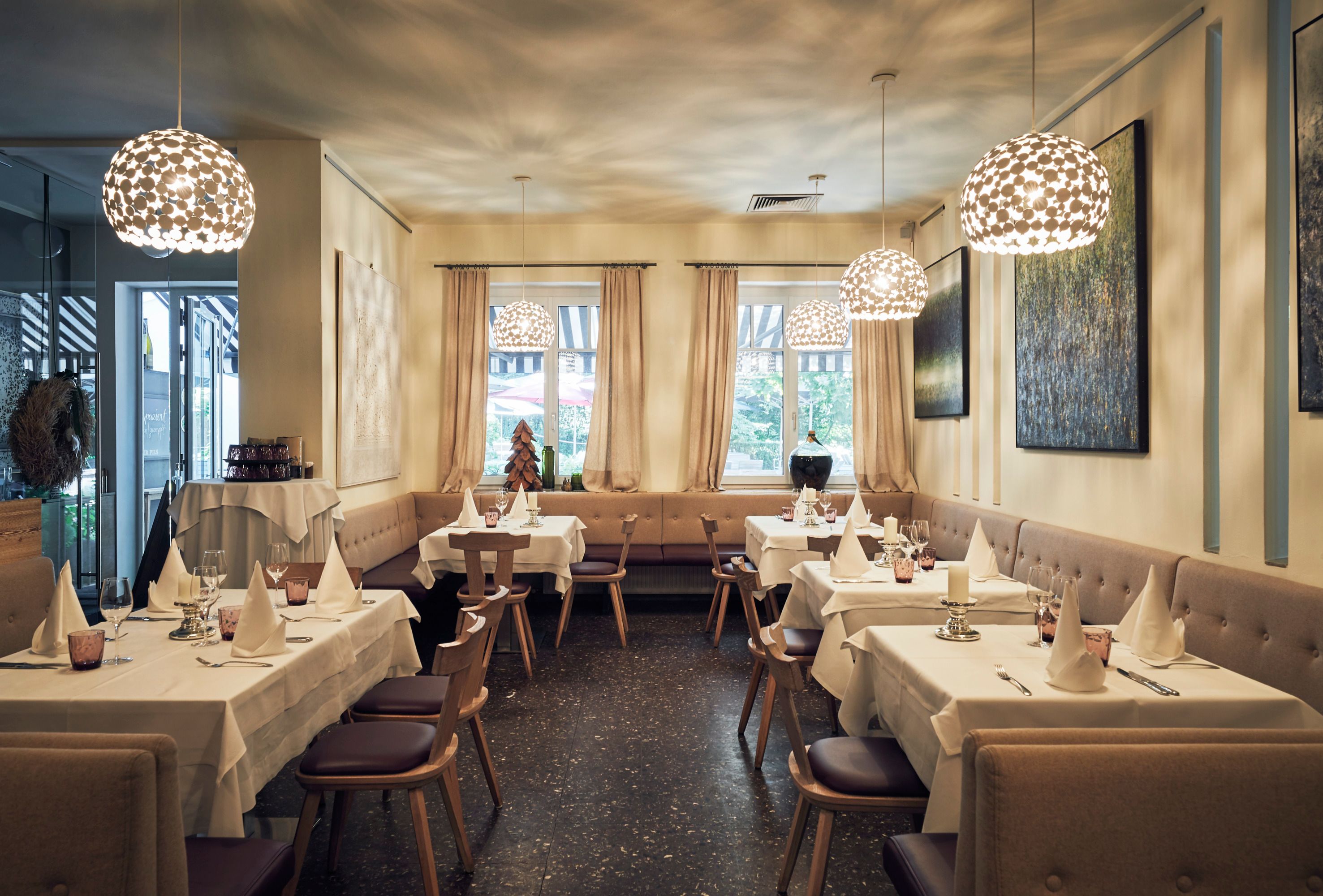 Elegantes Restaurant mit gedeckten Tischen, modernen Lampen und Kunst an den Wänden.