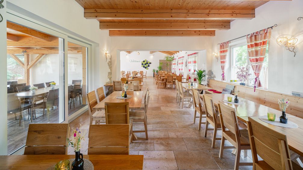 Innenansicht eines gemütlichen Heurigenlokals mit Holzmöbeln und dekorativen Vorhängen.