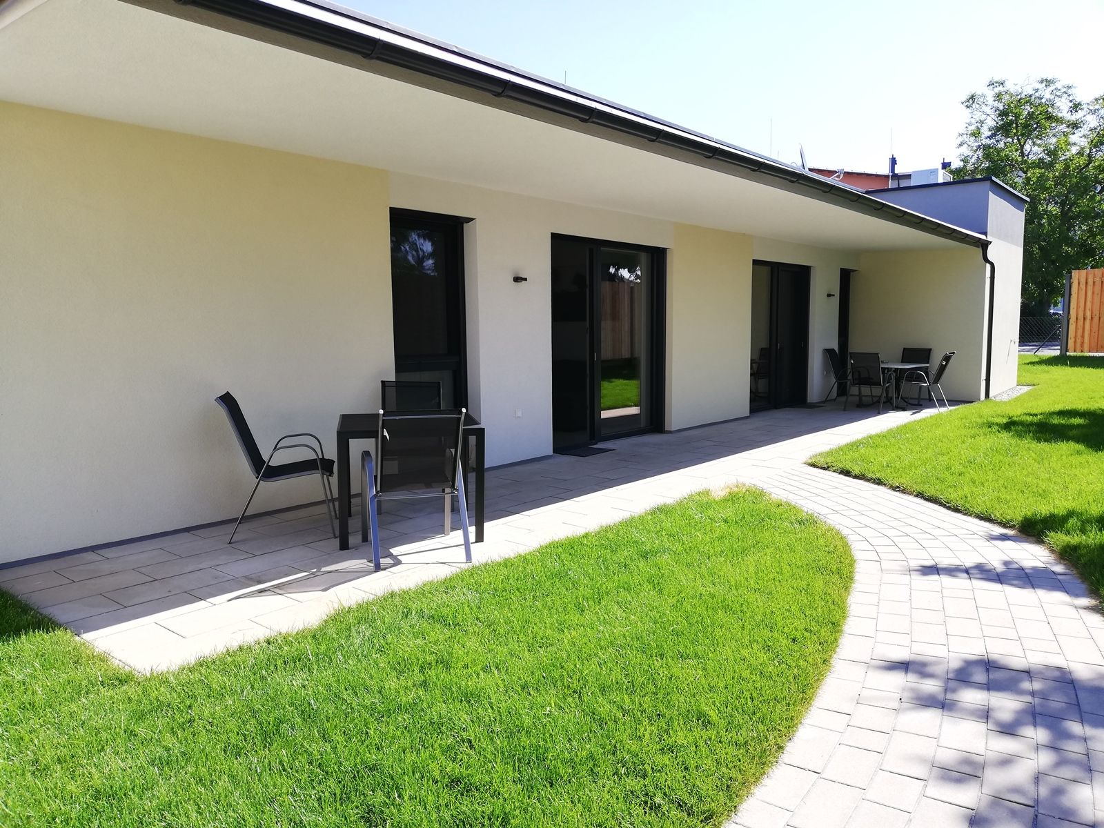 Terrasse eines modernen Ferienbungalows mit Gartenmöbeln und gepflegtem Rasen.