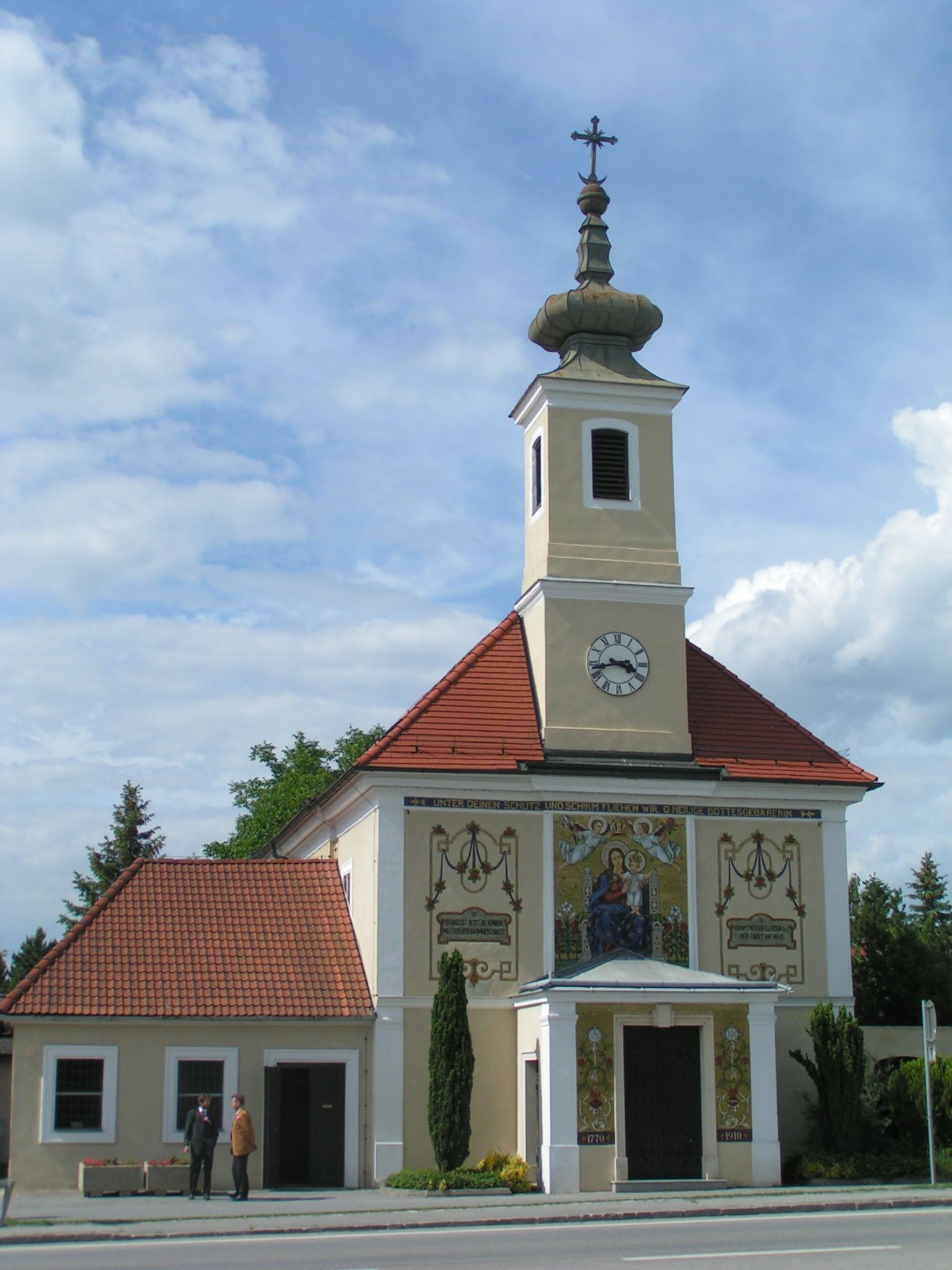 Wallfahrtskirche Maria Ellend mit Turm und Uhr, verziert mit religiösen Motiven.
