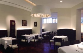 Elegantes Restaurant mit wei&szlig;en Tischdecken und moderner Beleuchtung.