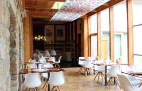 Innenansicht eines modernen Restaurants mit weißen Stühlen und Holztischen.