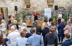 Eine Rednerin spricht beim Jubiläumsevent des Convention Bureau Niederösterreich in der Burg Perchtoldsdorf vor zahlreichen Gästen.