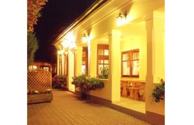 Beleuchteter Eingangsbereich eines traditionellen Gebäudes mit Säulen und Blumen.