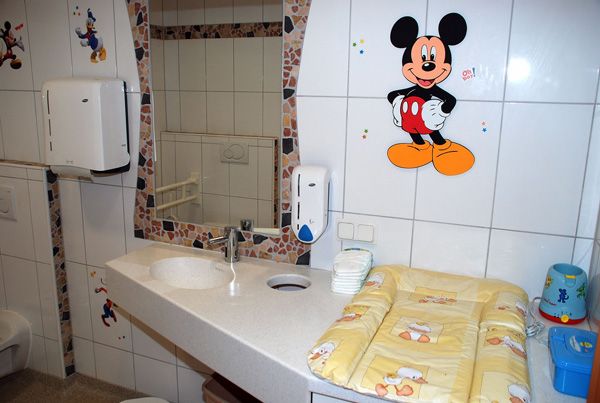 Kinderfreundliches Badezimmer mit Mickey-Mouse-Dekor und Wickeltisch.