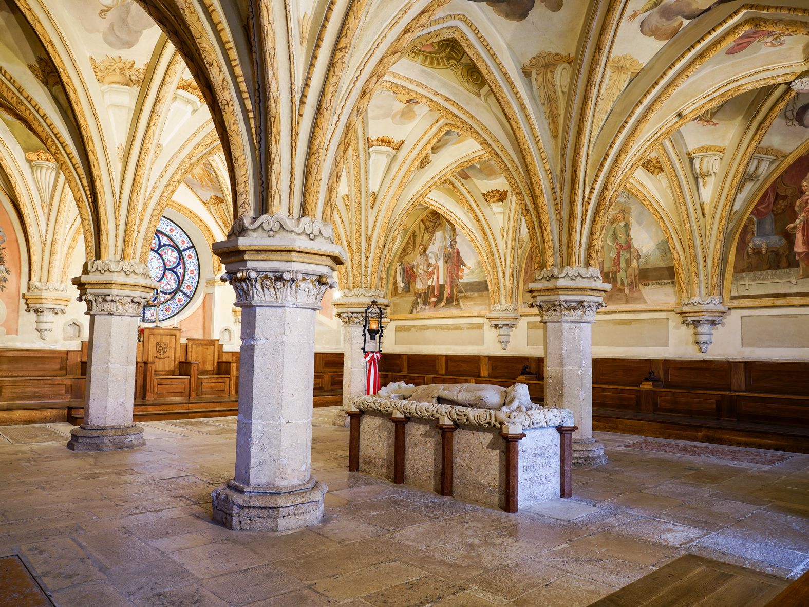 Innenansicht der Kapitelsaal im Stift Heiligenkreuz mit gotischen Gewölben und einem steinernen Sarkophag.