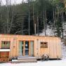 Kleines Holzhaus im Winterwald mit Schnee bedeckt.