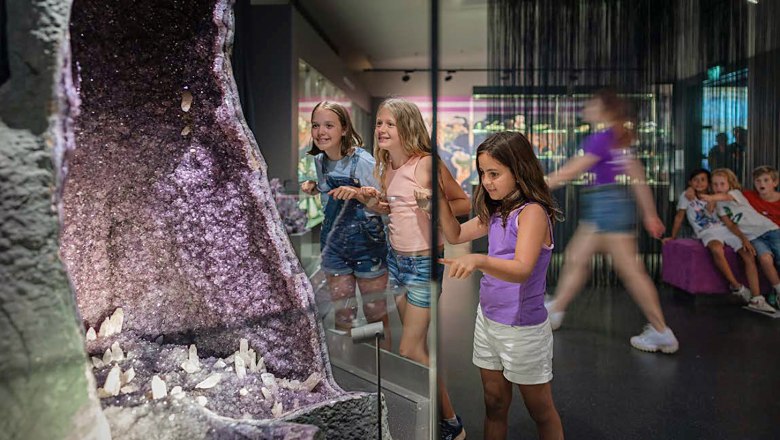 Kinder betrachten eine große Amethystgeode in einem Museum.