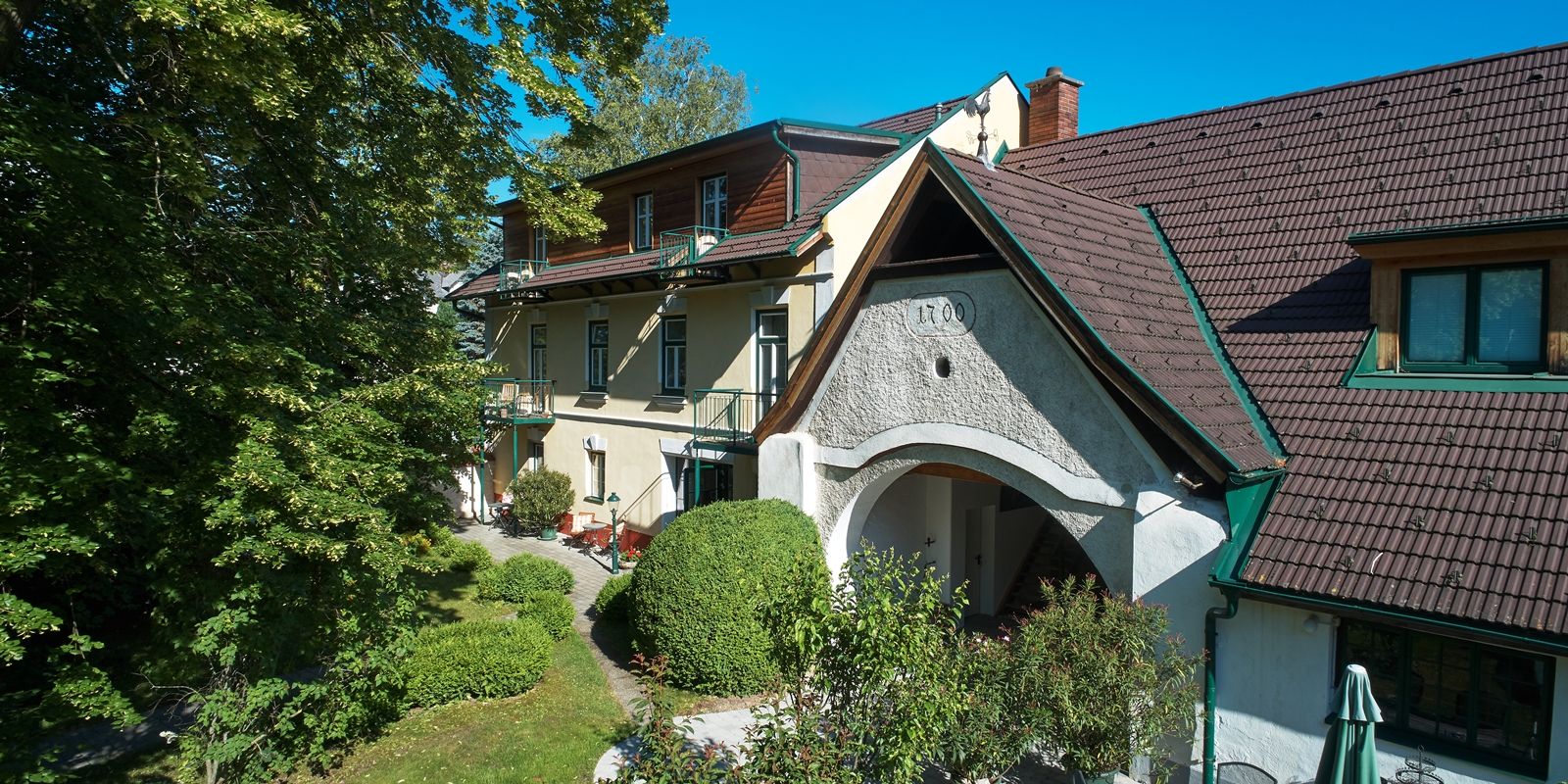 Landhaus Puchbergerhof mit Garten und Bäumen im Vordergrund.
