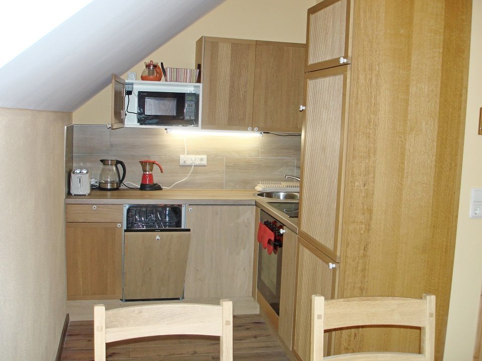 Kleine Küche in einer Ferienwohnung mit Holzschränken, Mikrowelle, Kaffeemaschine und Spüle.