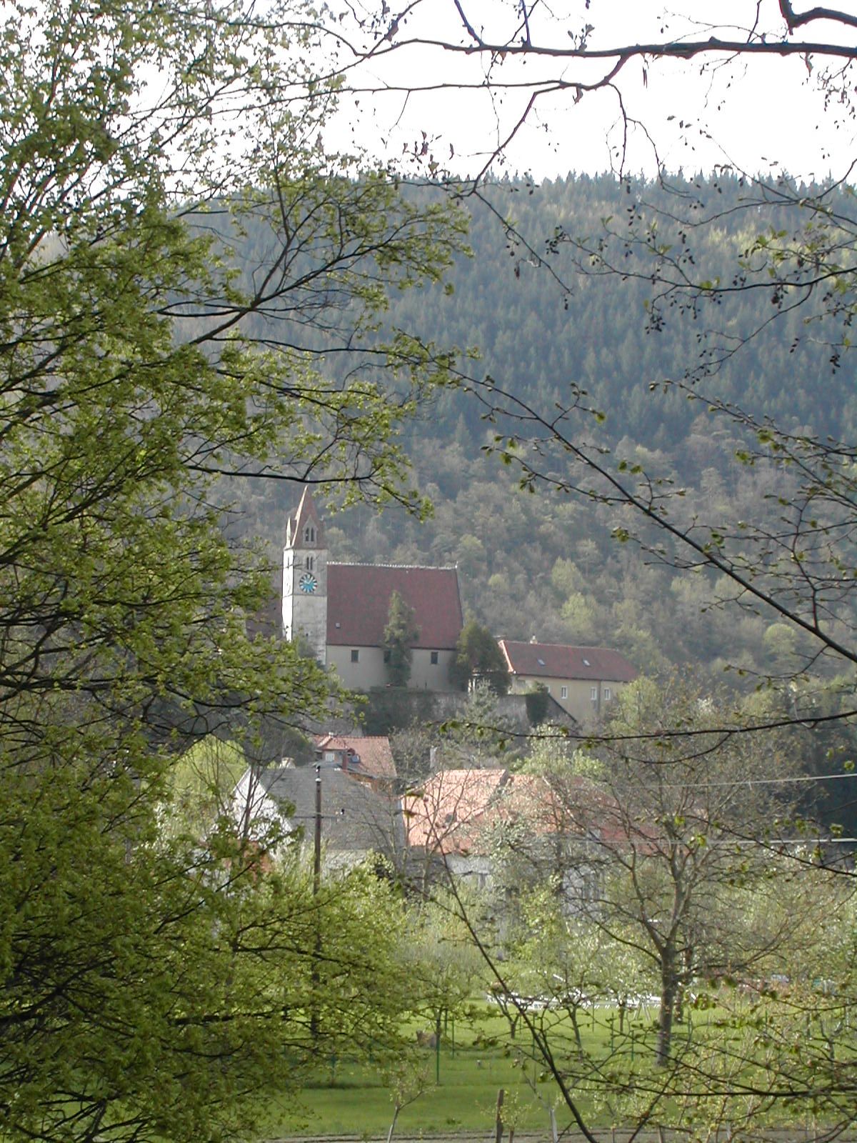 Pfarrkirche Senftenberg umgeben von Bäumen und Hügeln.