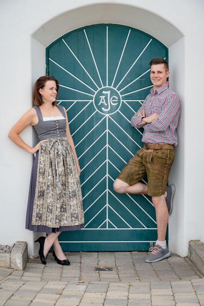Ein Mann und eine Frau in traditioneller Kleidung vor einer grünen Tür mit geometrischem Muster.
