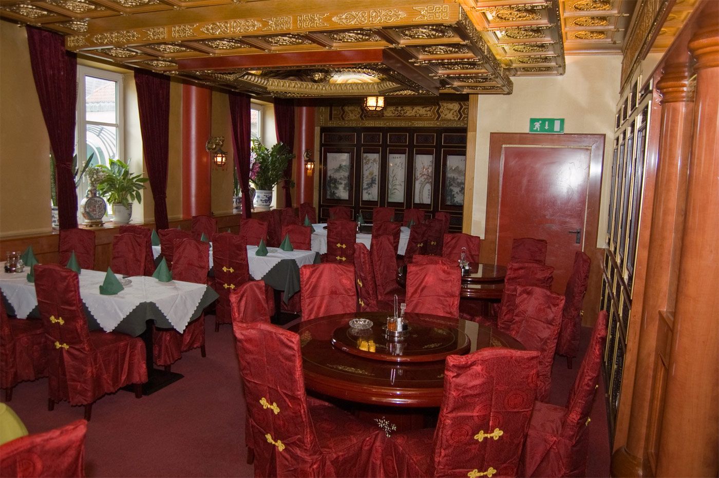 Elegantes Restaurant mit roten Stühlen und dekorativer Decke.