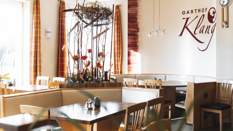 Innenansicht eines Restaurants mit Holzm&ouml;beln und dekorativen Pflanzen.