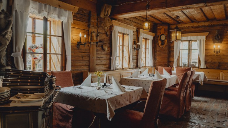 Innenansicht eines rustikalen Restaurants mit Holzwänden und gedeckten Tischen.