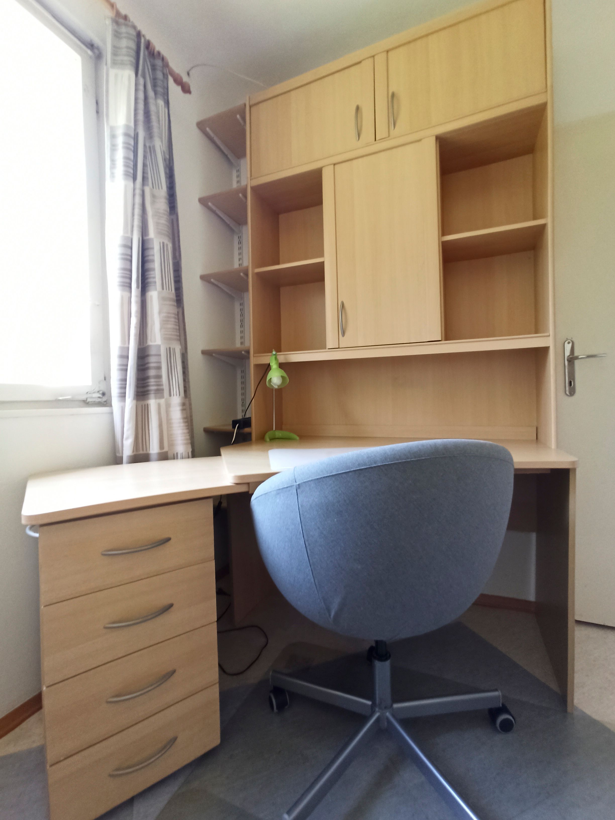Ein moderner Schreibtisch mit einem grauen Bürostuhl und einem Regal mit Schubladen und Fächern.
