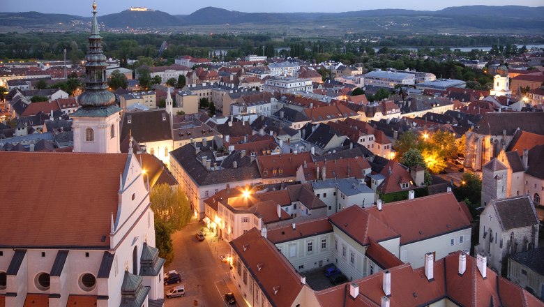 Abendliche Stadtansicht von Krems mit beleuchteten Geb&auml;uden und H&uuml;geln im Hintergrund.