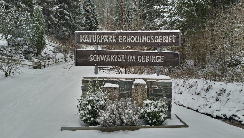 Eingangsschild des Naturparks Schwarzau im Gebirge im Winter mit Schnee bedeckt.