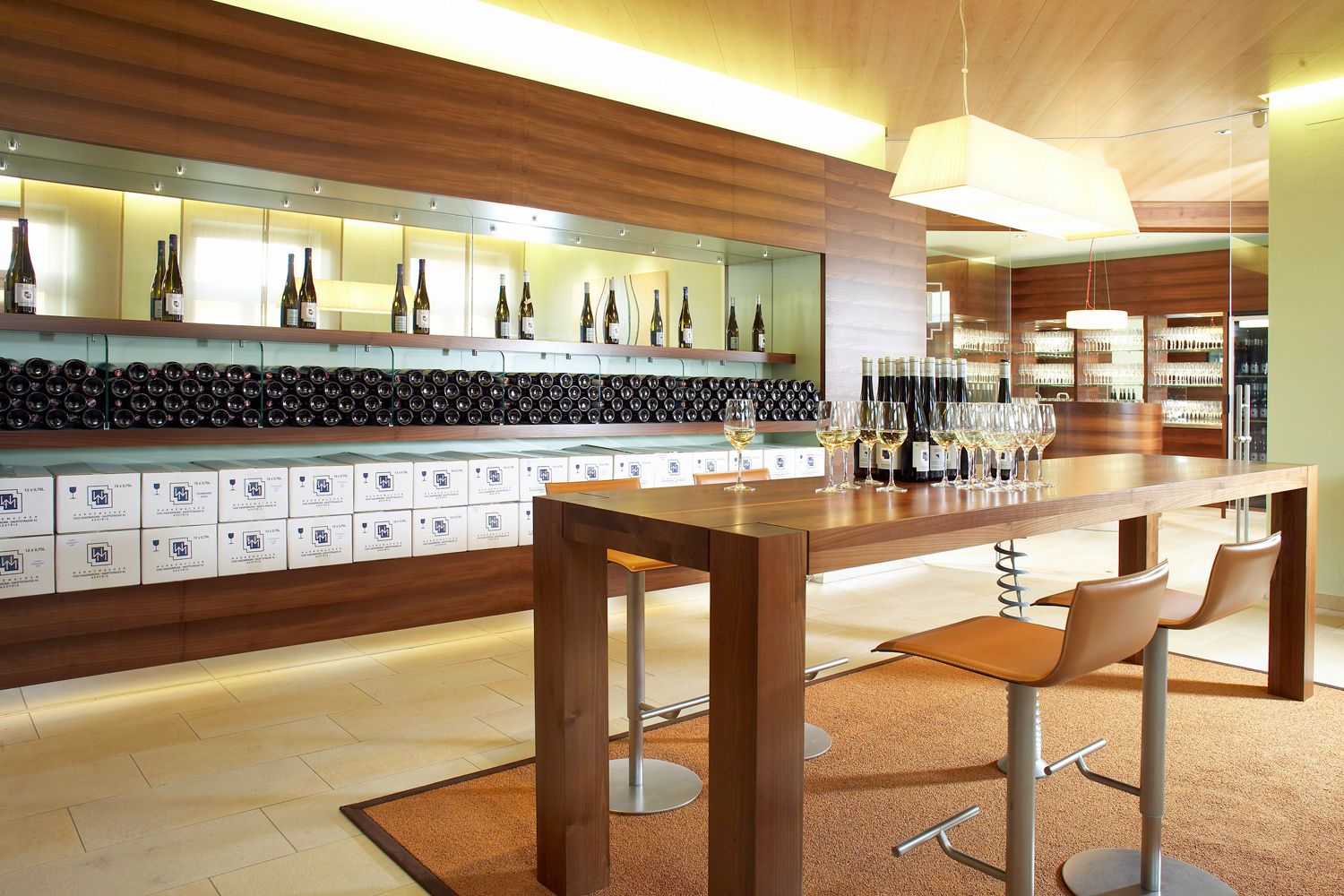 Moderner Verkostungsraum mit Holztisch, Weingläsern und Weinflaschen.