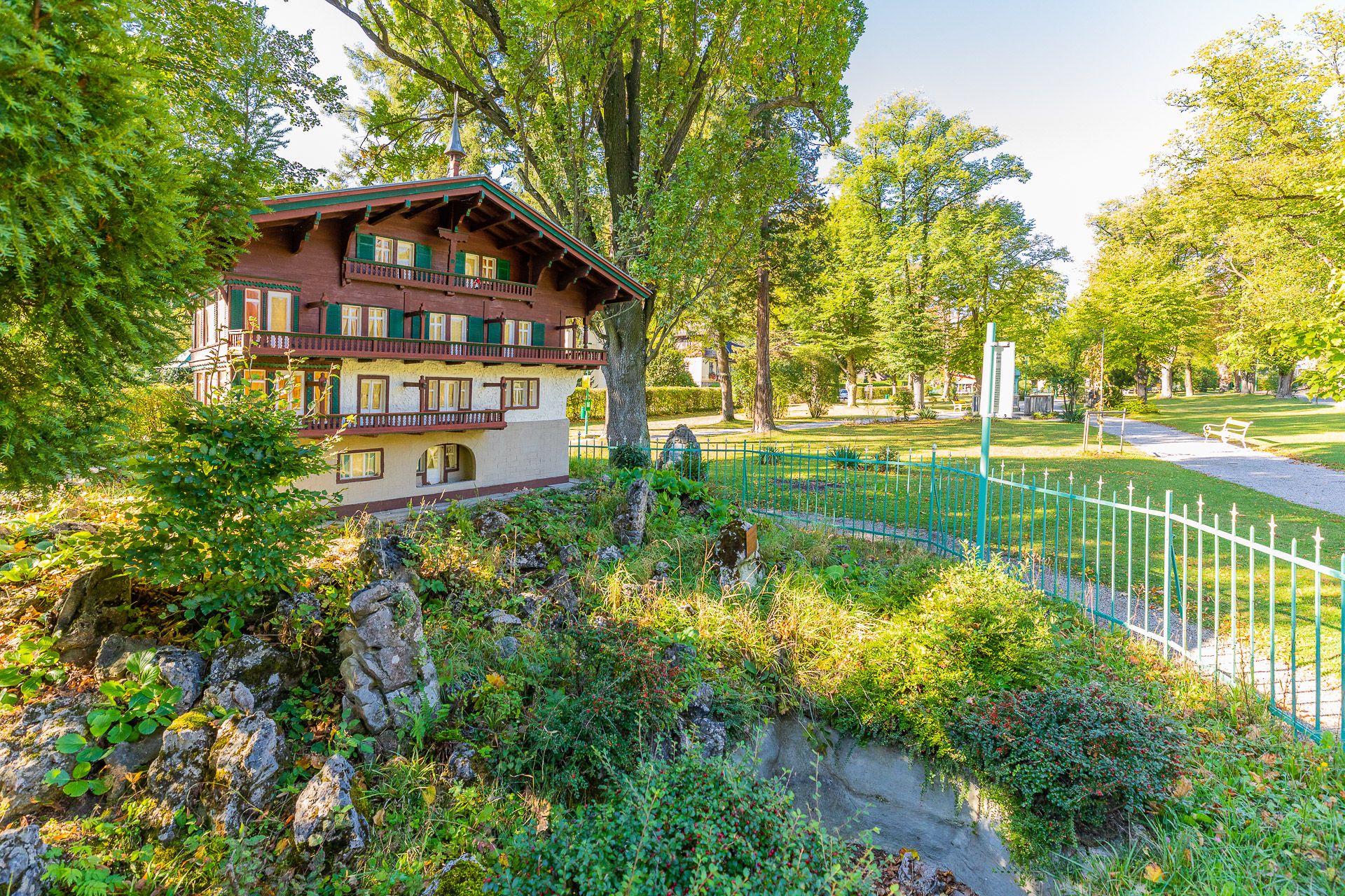 Miniaturhaus in einem Park mit Bäumen und einem Weg.