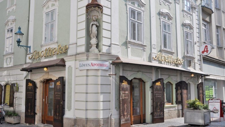 Historische Apotheke mit grüner Fassade und goldener Schrift in einer Stadt.