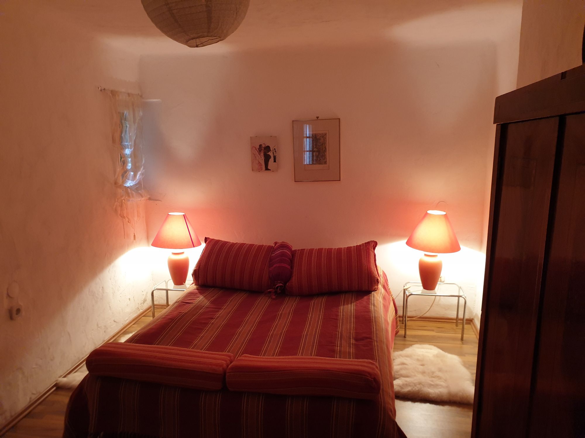 Gemütliches Schlafzimmer mit Doppelbett, roten Lampen und Holzmöbeln.
