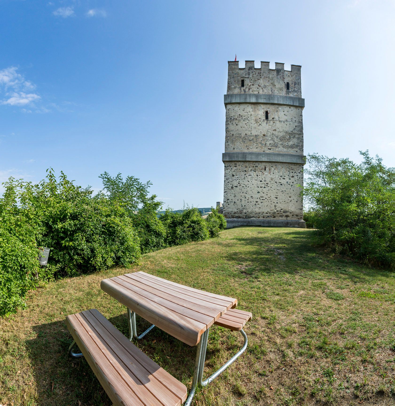 Feuerturm der Burgruine Kirchschlag mit Picknicktisch im Vordergrund.