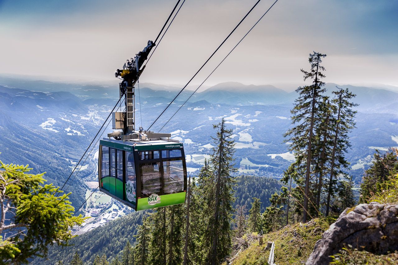 Seilbahn in den Bergen mit Blick auf bewaldete Hänge und Täler.