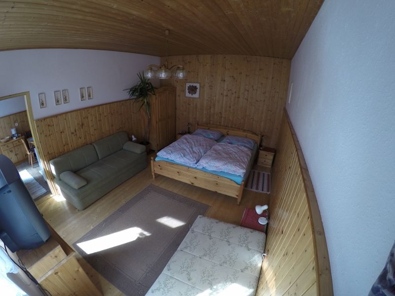 Ein gemütliches Schlafzimmer mit Holzwänden, einem Doppelbett, einem Sofa und einem Teppich auf Holzboden.