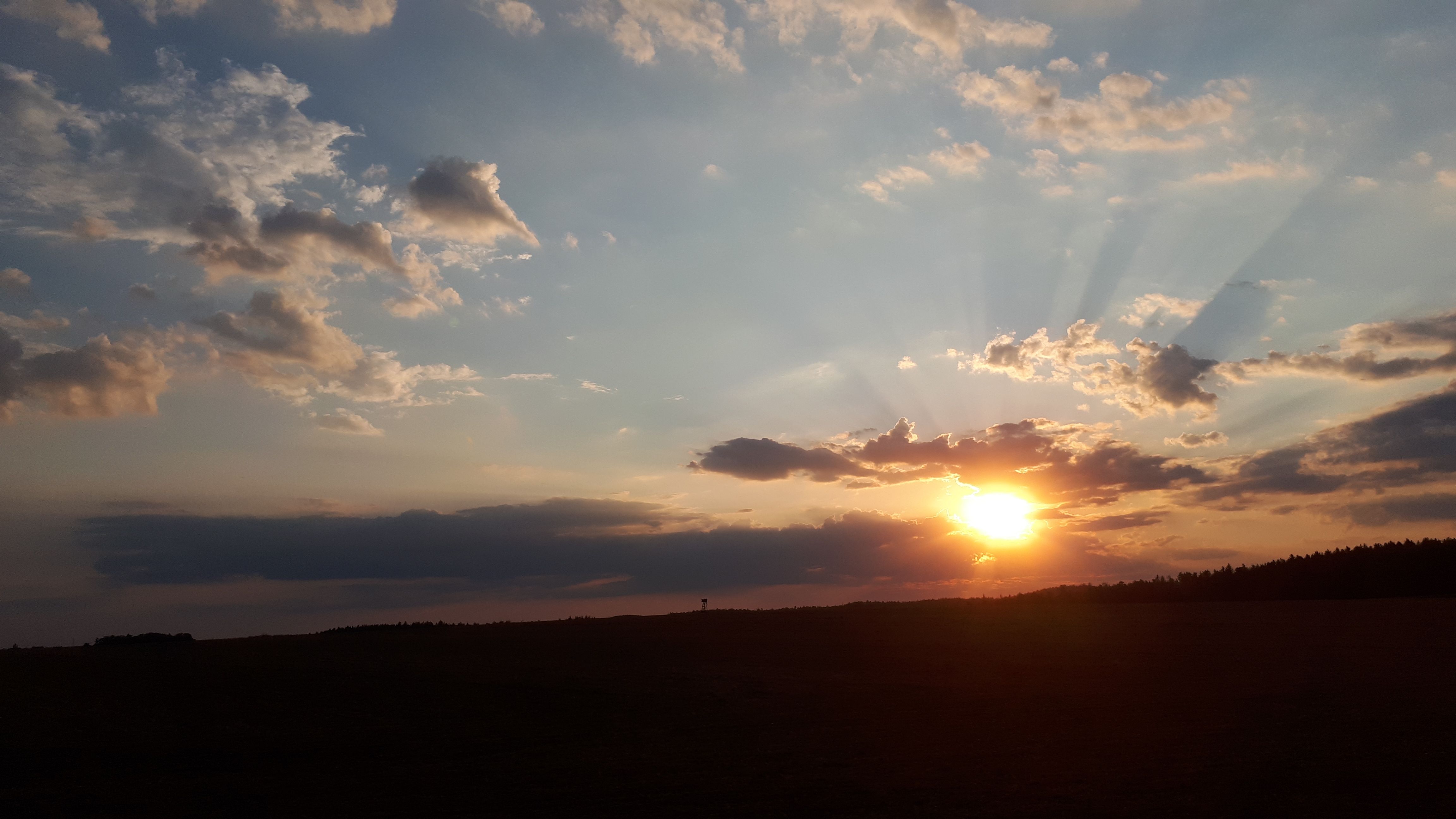 Sonnenuntergang mit Wolken und Strahlen am Himmel.