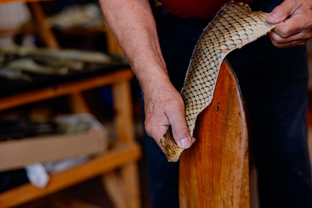 Person bearbeitet Fischleder auf einem Holzwerkzeug.
