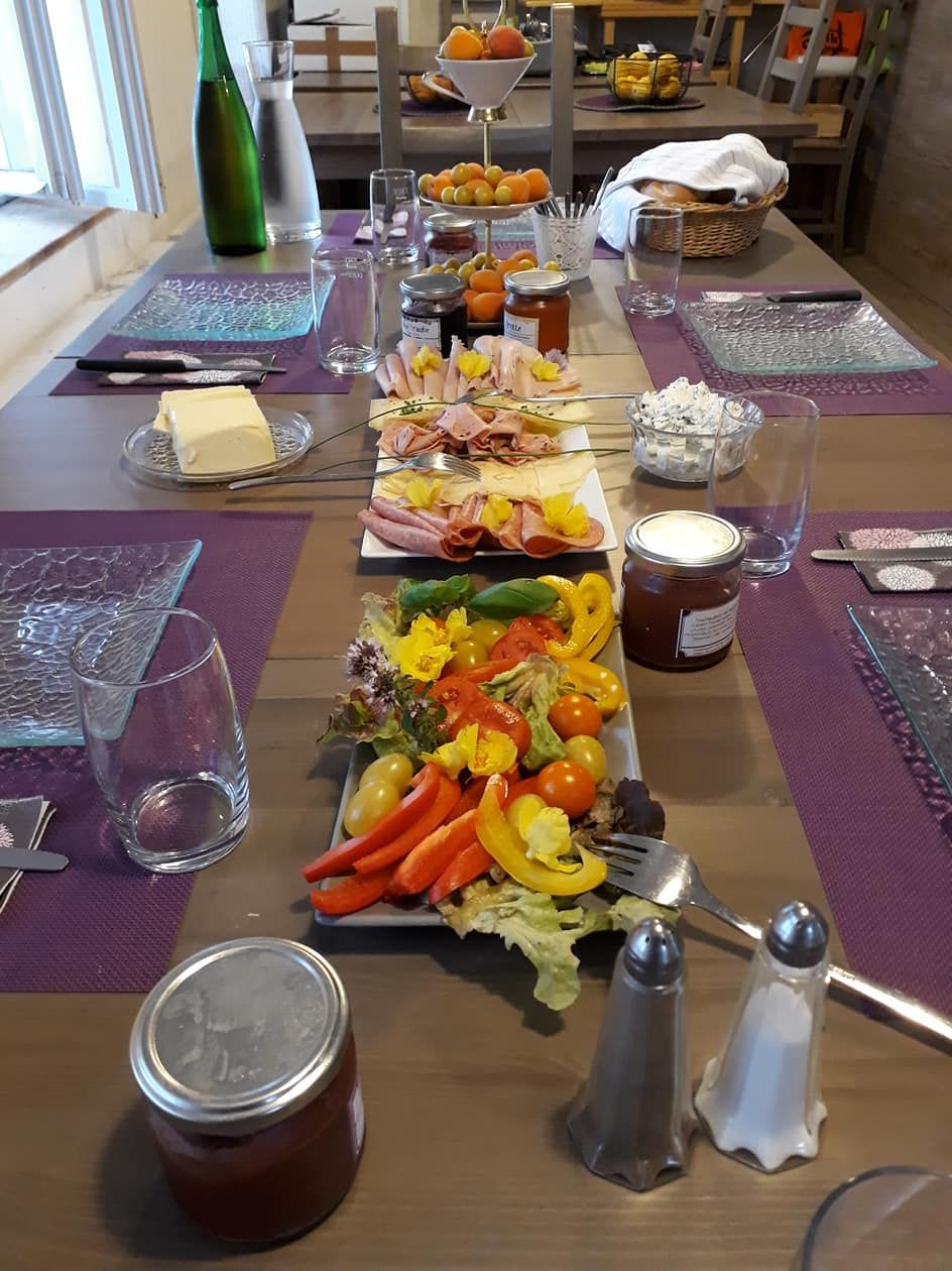 Ein gedeckter Frühstückstisch mit Aufschnitt, Gemüse, Marmelade und Getränken.