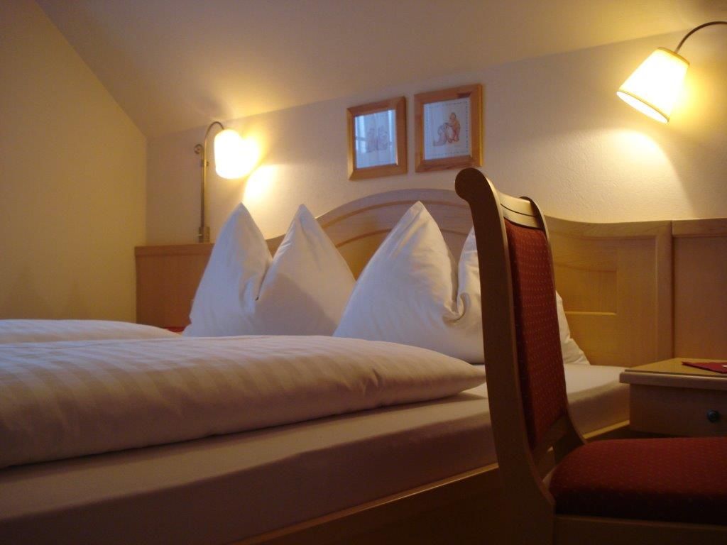 Gemütliches Gästezimmer mit Doppelbett, zwei Nachttischlampen und einem Stuhl.