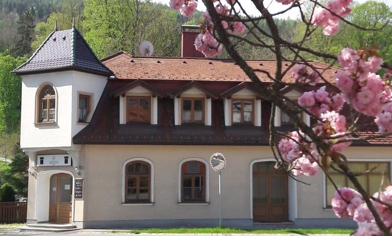 Ein zweistöckiges Gebäude mit einem Turm und blühenden Kirschblüten im Vordergrund.