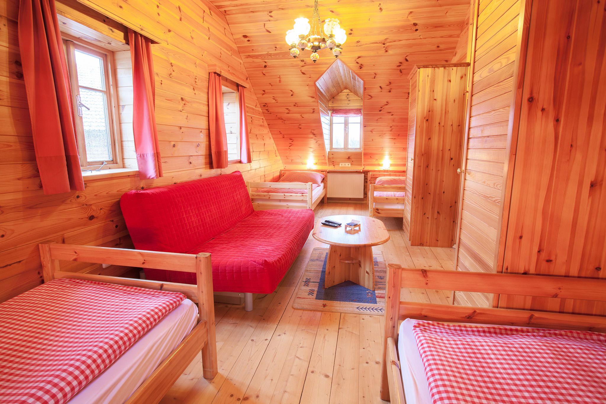Holzvertäfeltes Zimmer mit roten Vorhängen und Bettwäsche.