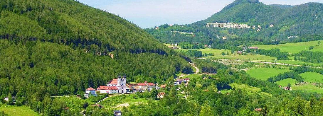 Landschaft mit Kirche und grünen Hügeln im Vordergrund.