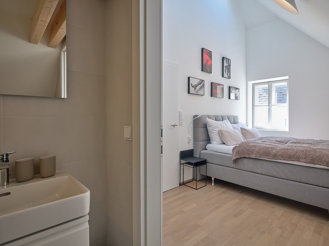 Modernes Schlafzimmer mit grauem Bett und angrenzendem Badezimmer.