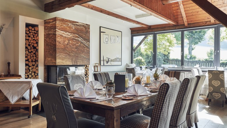 Elegantes Restaurant mit Holzbalken, Kamin und gedeckten Tischen.