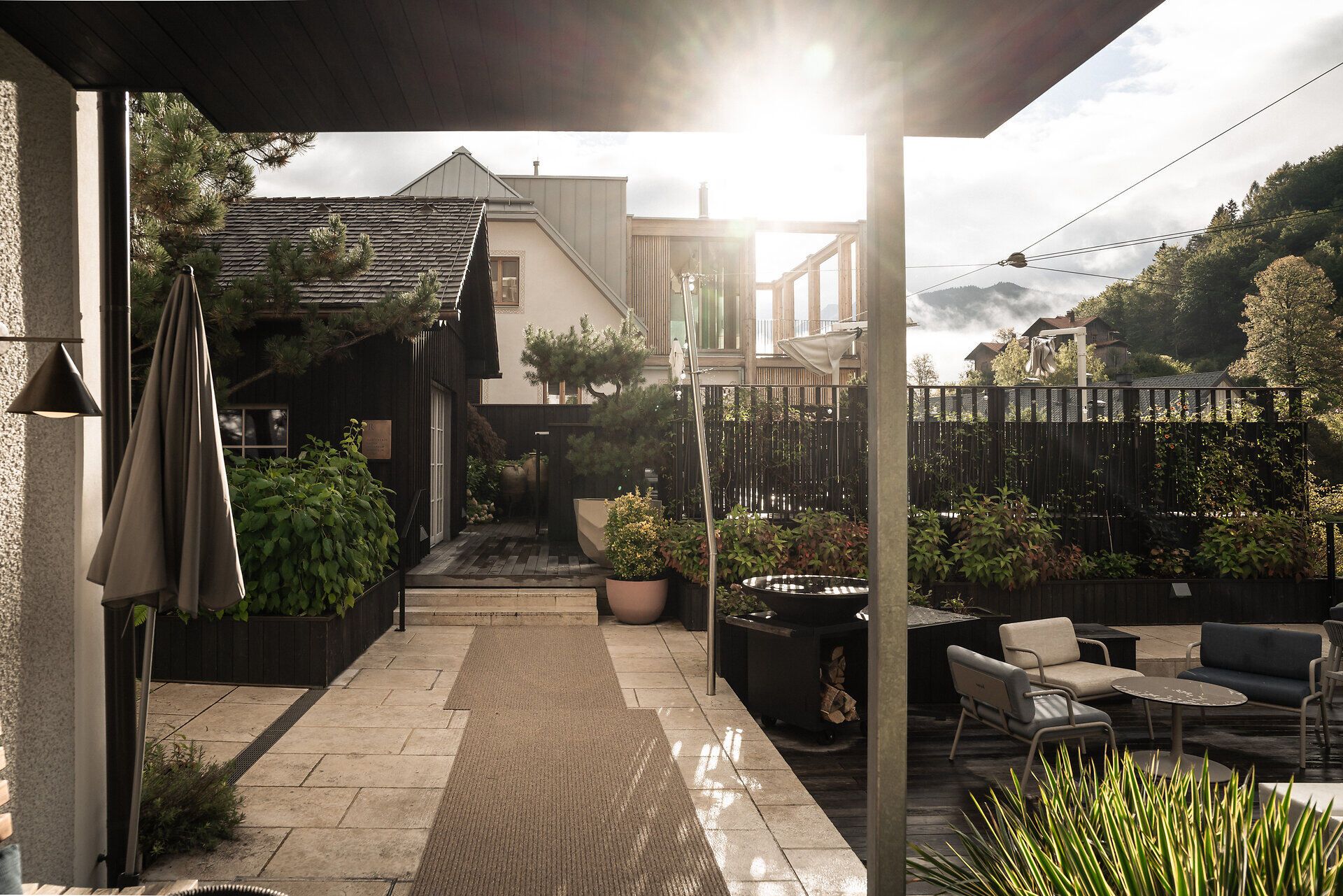 Terrasse mit Sitzbereich, Pflanzen und Sonnenschirmen im Refugium Lunz