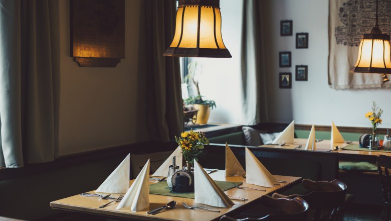 Gem&uuml;tliche, traditionell eingerichtete Stube mit gedeckten Tischen und warmem Licht.